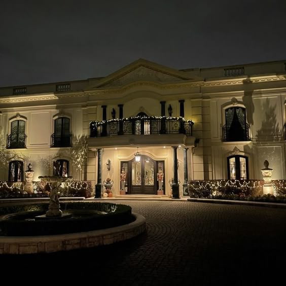 This may contain: a large white house lit up at night with christmas lights on the windows and balconies