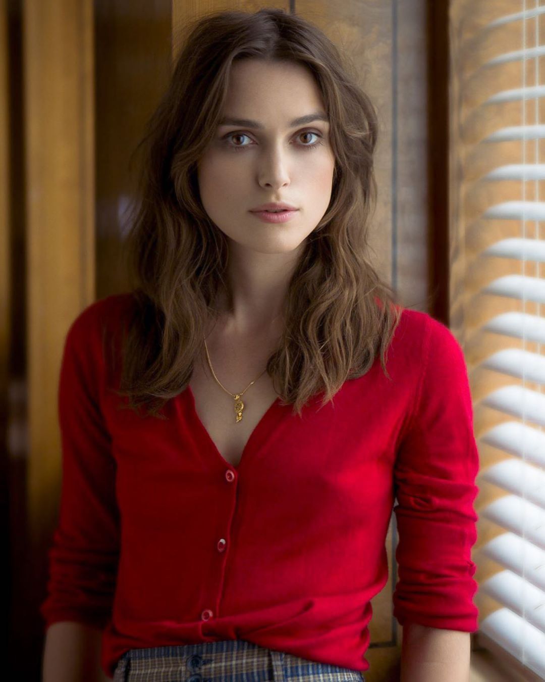 Keira Knightley looking thoughtful in a red cardigan