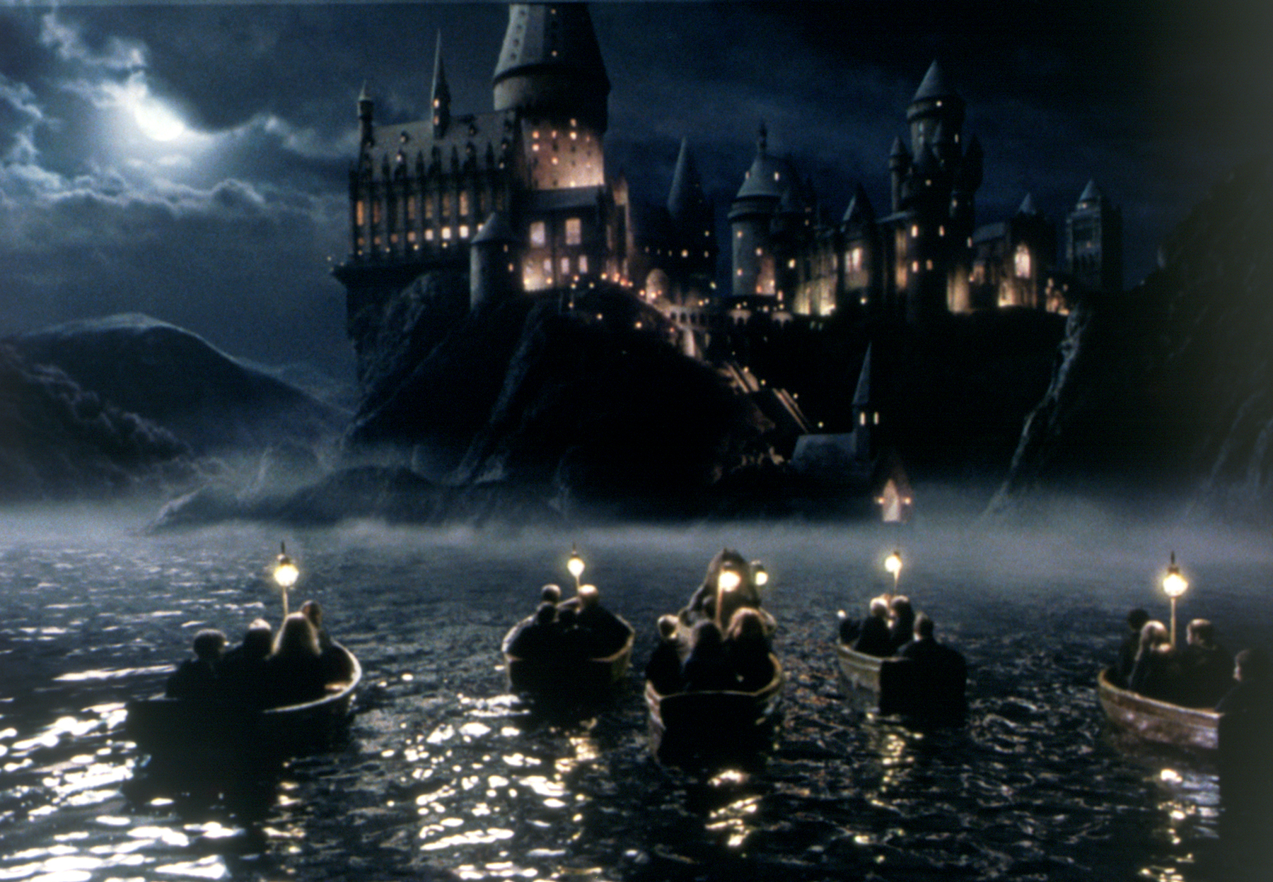 Hogwarts Castle illuminated above the lake at night